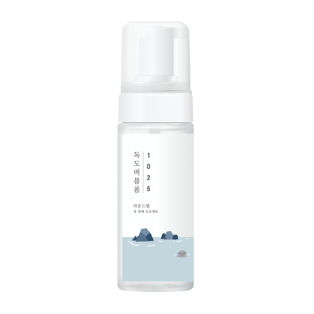 1025 Dokdo Bubble Foam" è un prodotto per la pulizia del viso di ROUND LAB, confezionato in un flacone a pompa bianco con un design semplice e pulito, ornato con testo e illustrazioni minimaliste di paesaggi marini. 