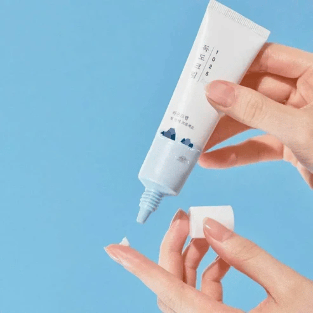Round Lab 1025 Dokdo Eye Cream tubo con crema leggera applicata sulla punta del dito per una cura delicata della pelle sensibile intorno agli occhi