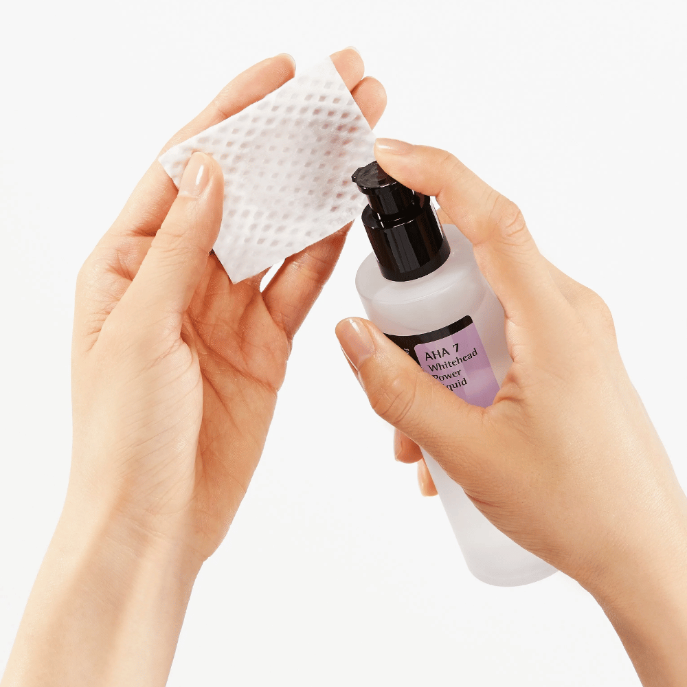 Applicazione di COSRX AHA 7 Whitehead Power Liquid su un dischetto di cotone, tonico esfoliante con AHA per rimuovere le cellule morte della pelle e migliorare la struttura della pelle.