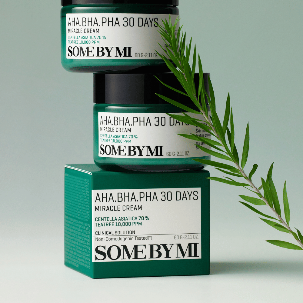 Un'immagine che mostra due barattoli di "SOME BY MI AHA, BHA, PHA 30 Days Miracle Cream" impilati su una scatola tonalità verde. La crema, ricca di centella asiatica e olio di tea tree, è progettata per migliorare la qualità della pelle e alleviare i problemi cutanei. Ha un effetto idratante e lenitivo.