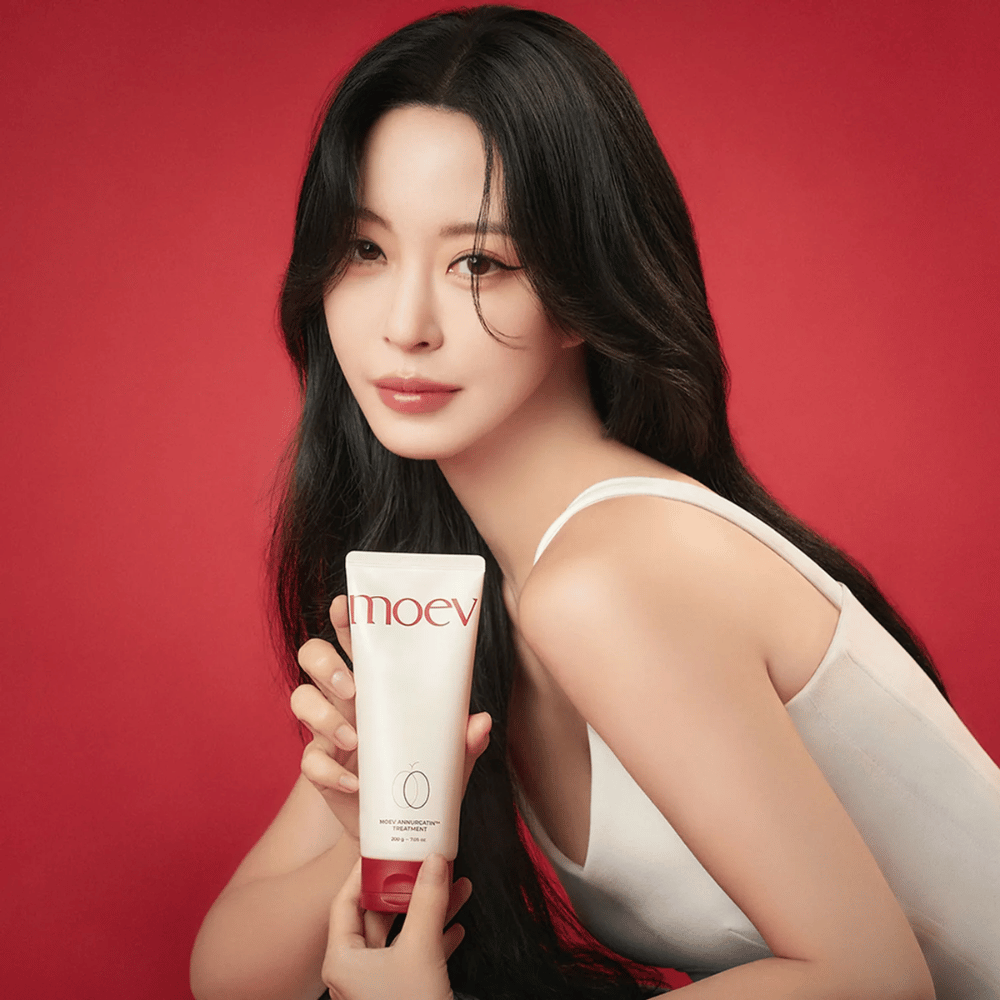 Donna con capelli lunghi e lucenti tiene MOEV Annurcatin Treatment – trattamento per capelli coreano che fornisce nutrimento, forza e lucentezza con ingredienti naturali.