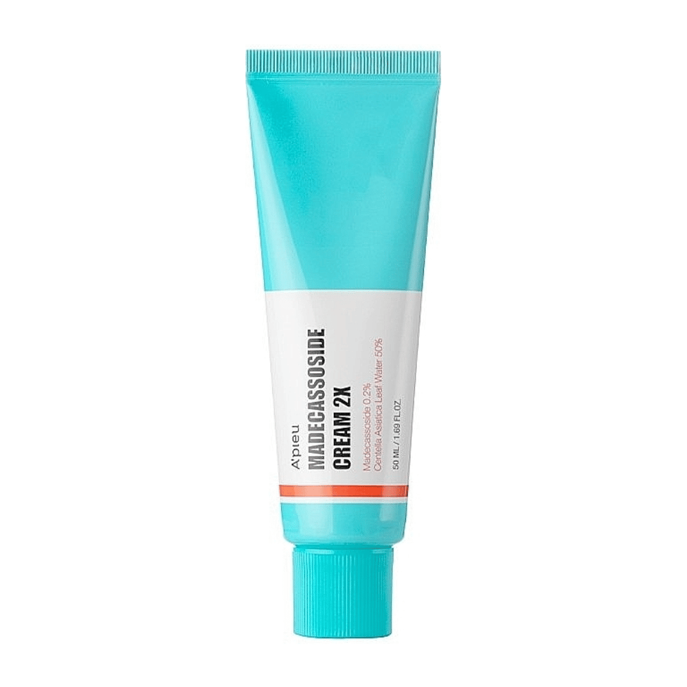 Un tubo con A'PIEU Madecassoside Cream 2X, con un colore turchese chiaro sulla parte superiore che sfuma in bianco verso il basso. Il tubo ha un testo chiaro che indica il marchio e il nome del prodotto, oltre all'ingrediente attivo Madecassoside 2%. Un accento arancione corre come una striscia intorno al tubo. Il prodotto sembra essere una crema per la pelle focalizzata sulla cura e la riparazione della pelle. Lo sfondo è neutro per mantenere l'attenzione sul prodotto.