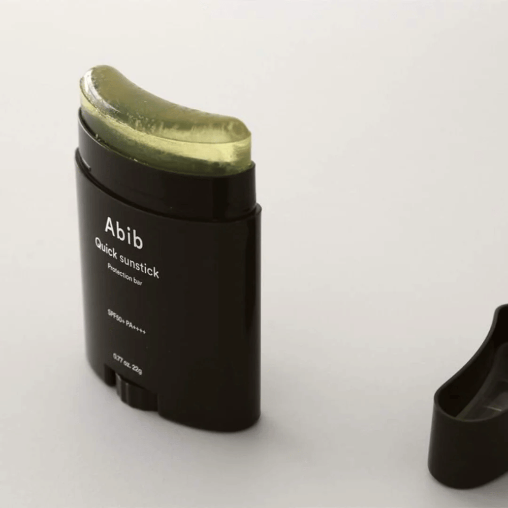 Un tubo nero con tappo verde, contenente Quick Sunstick Protection Bar SPF50+ PA++++ 22g da Abib per la protezione solare.