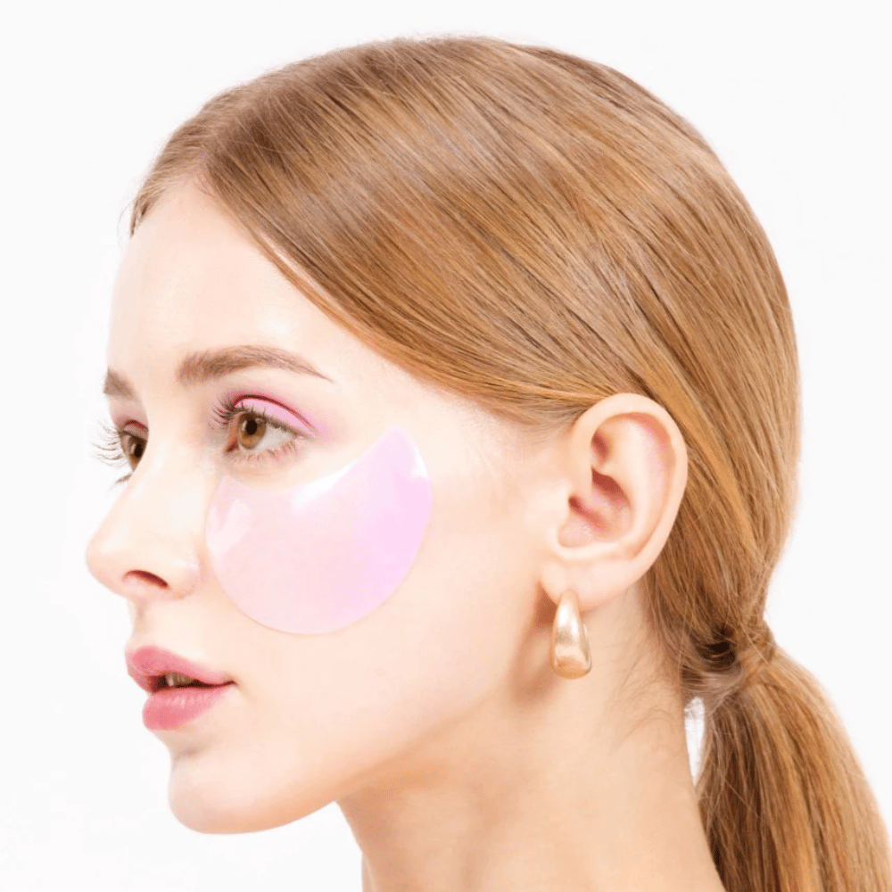 Modello indossa un idrogel rosa patch occhi sotto l'occhio, idratante e ringiovanente per la pelle.