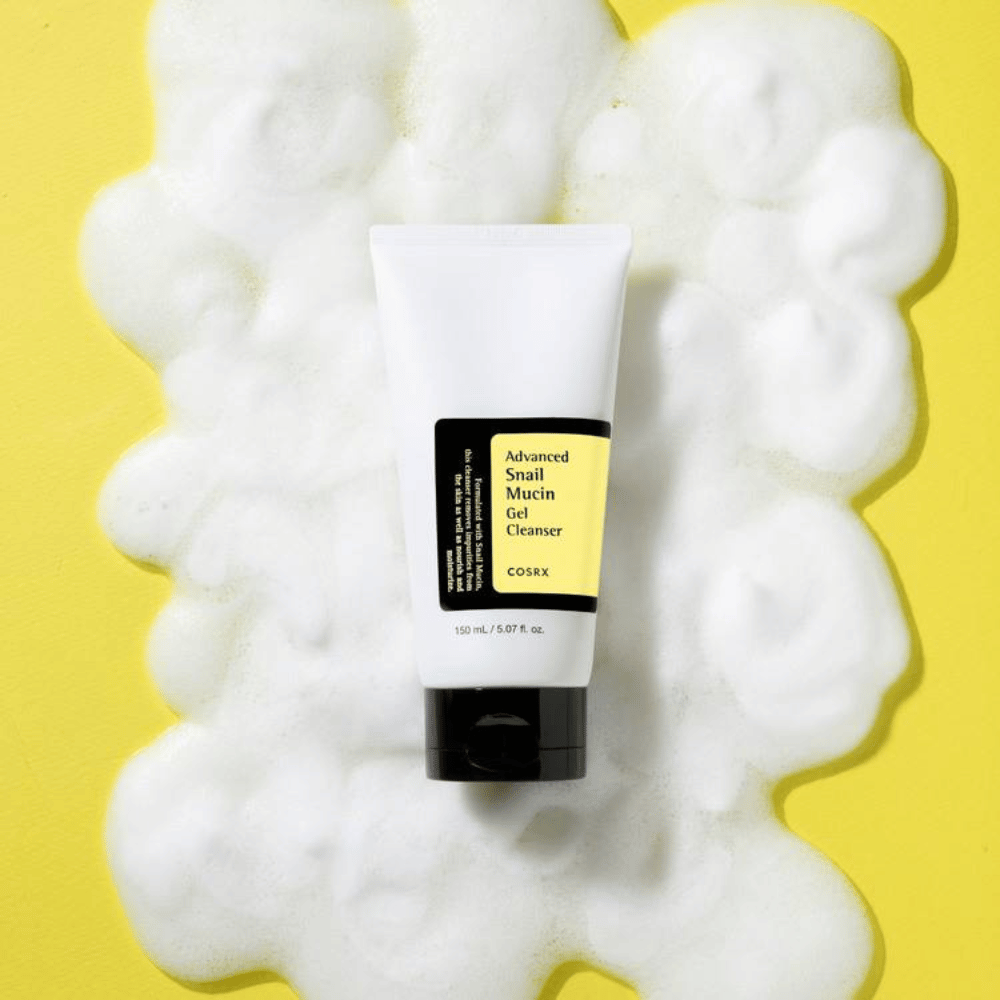 COSRX Advanced Snail Mucin Gel Cleanser 150 ml circondato da abbondante schiuma su sfondo giallo – delicato detergente viso coreano con bava di lumaca per idratazione e luminosità.