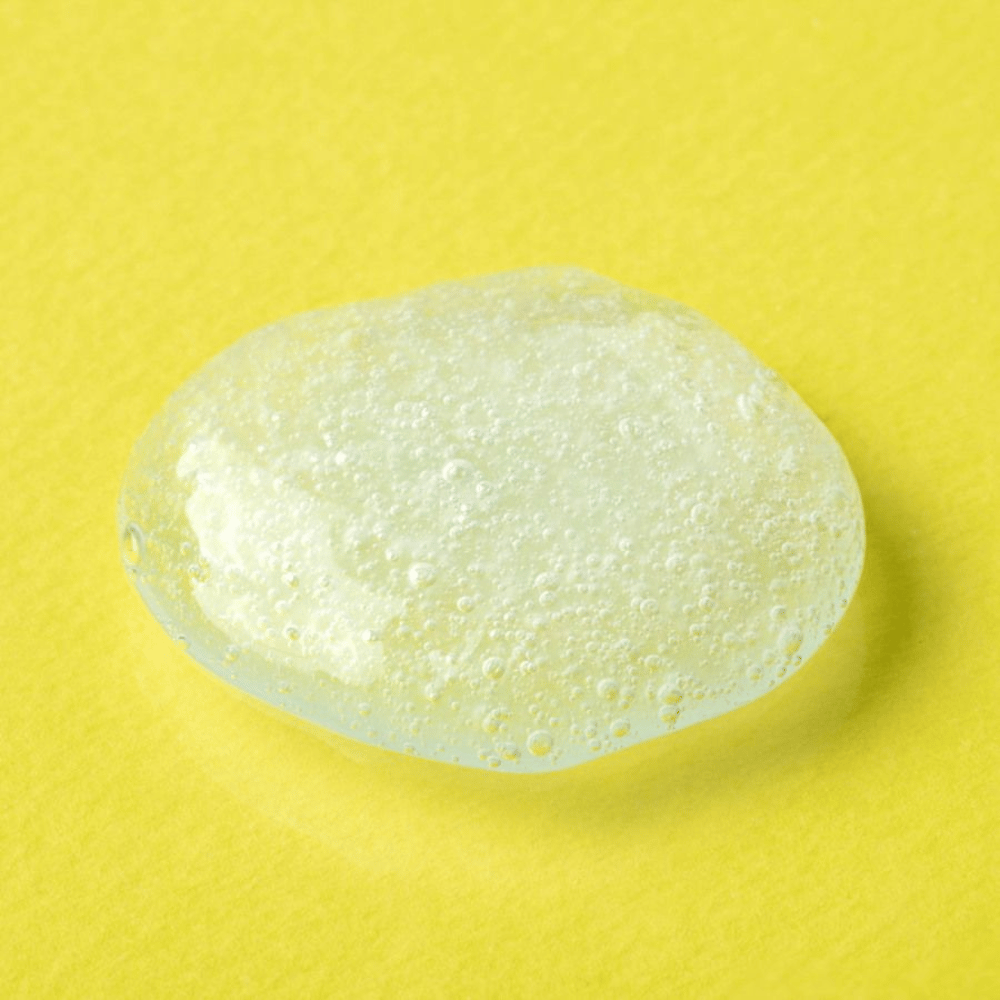 Texture gel trasparente da COSRX Advanced Snail Mucin Gel Cleanser su sfondo giallo – detergente viso idratante con secrezione di lumaca per pelle morbida ed equilibrata.