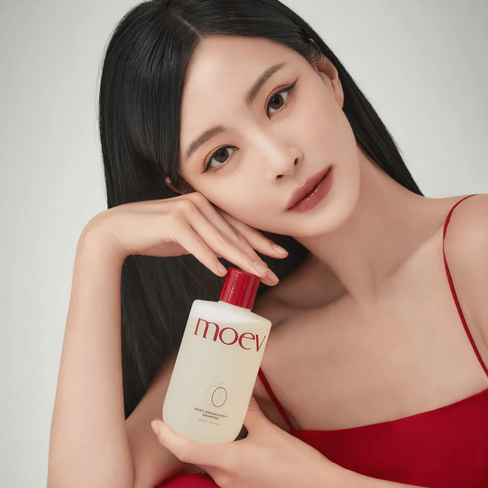 Donna con capelli lunghi e lucenti tiene MOEV Annurcatin Shampoo – uno shampoo coreano che idrata, rinforza e protegge i capelli con ingredienti naturali.