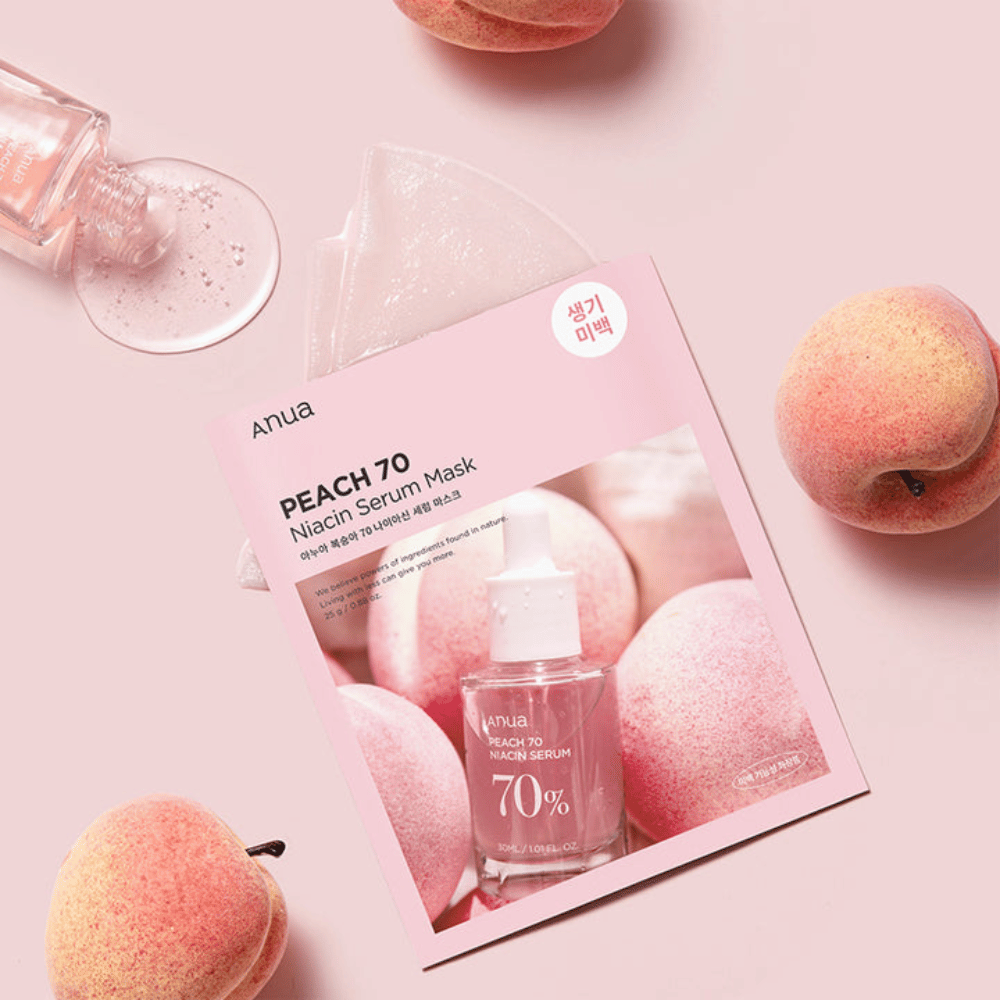 Un'immagine di Anua PEACH 70 Niacin Serum Mask, circondata da pesche e una bottiglia di siero. L'immagine ha uno sfondo rosa tenue, che completa la confezione rosa e mette in risalto il prodotto e gli ingredienti.