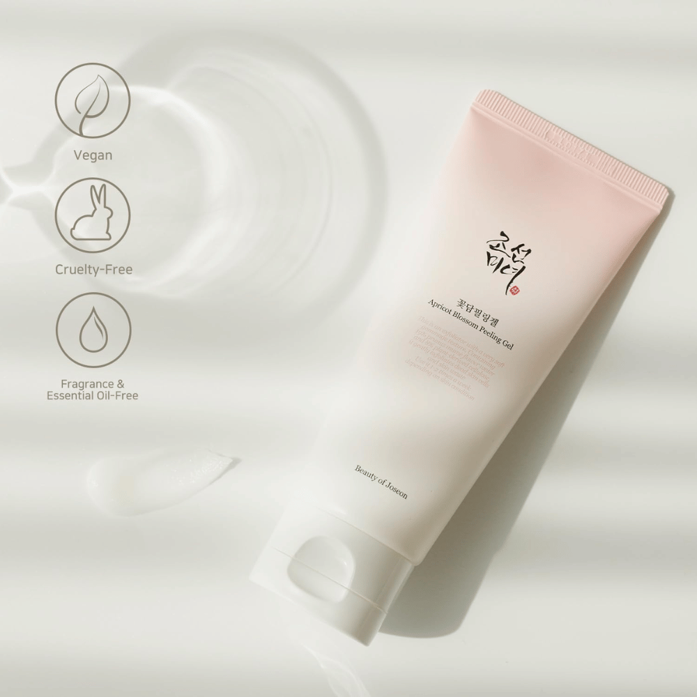 Un tubo con Apricot Blossom Peeling Gel si trova su una superficie riflettente con icone che indicano che il prodotto è vegano, amico degli animali e privo di profumi e oli essenziali.