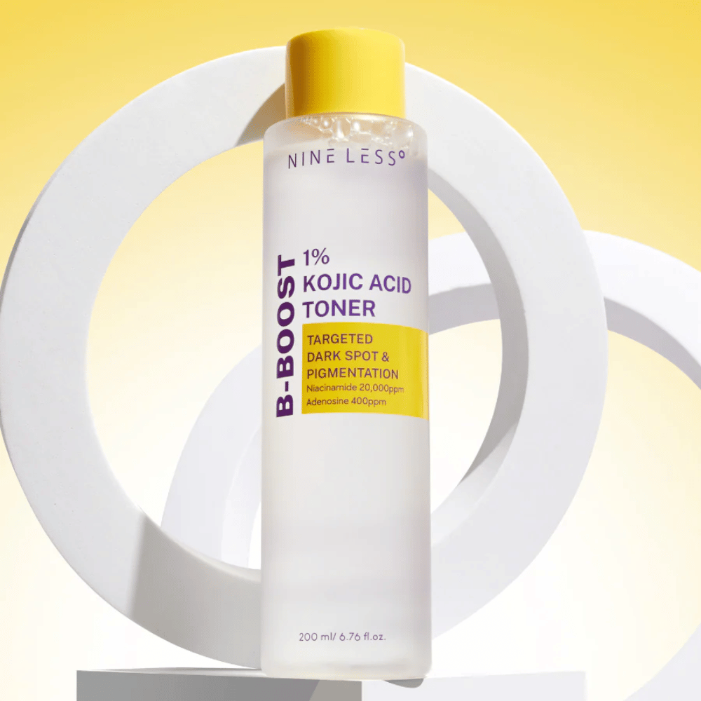 NINE LESS B-Boost 1% Kojic Acid Toner contro uno sfondo giallo con il testo "Targeted Dark Spot & Pigmentation". tonico viso uniformante del tono della pelle con niacinamide e adenosina.