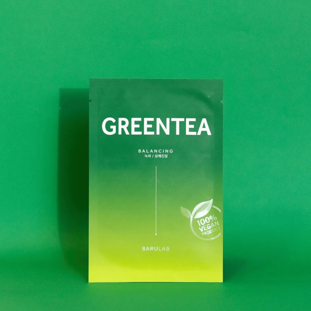 Una confezione da BARULAB per una maschera "GREENTEA Balancing", etichettata come "100% Vegan Product". Il colore della confezione passa dal verde scuro in alto al verde più chiaro in basso, su uno sfondo verde uniforme.