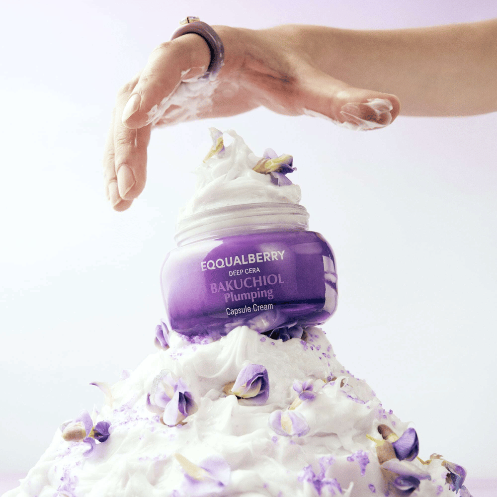 EQQUALBERRY Bakuchiol Plumping Capsule Cream posizionata sopra un cumulo di crema montata con petali di fiori - simboleggia idratazione e cura.