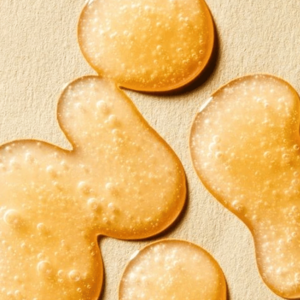 Immagine della texture che mostra la formula dorata del siero con piccole bolle e una consistenza leggera simile a un gel.
