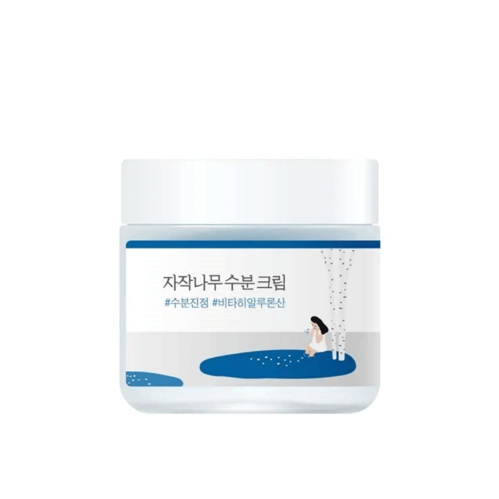 Round Lab Birch Juice Moisturizing Cream in barattolo trasparente con coperchio bianco ed etichetta blu con illustrazione di betulla e ragazza, isolato su sfondo bianco.