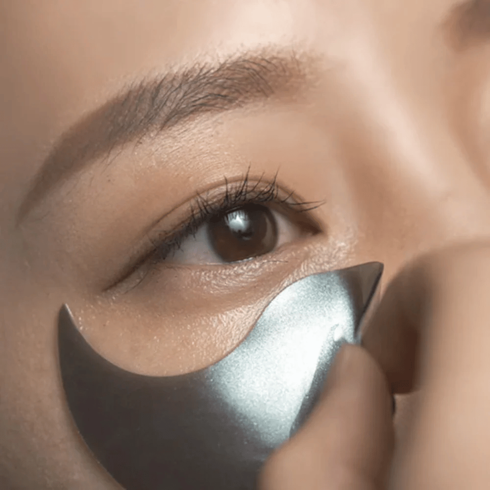Immagine dettagliata in cui un hydrogel nero patch occhi viene applicato sotto l’occhio. L’immagine mostra la vestibilità aderente e la sensazione rinfrescante intorno alla zona degli occhi.