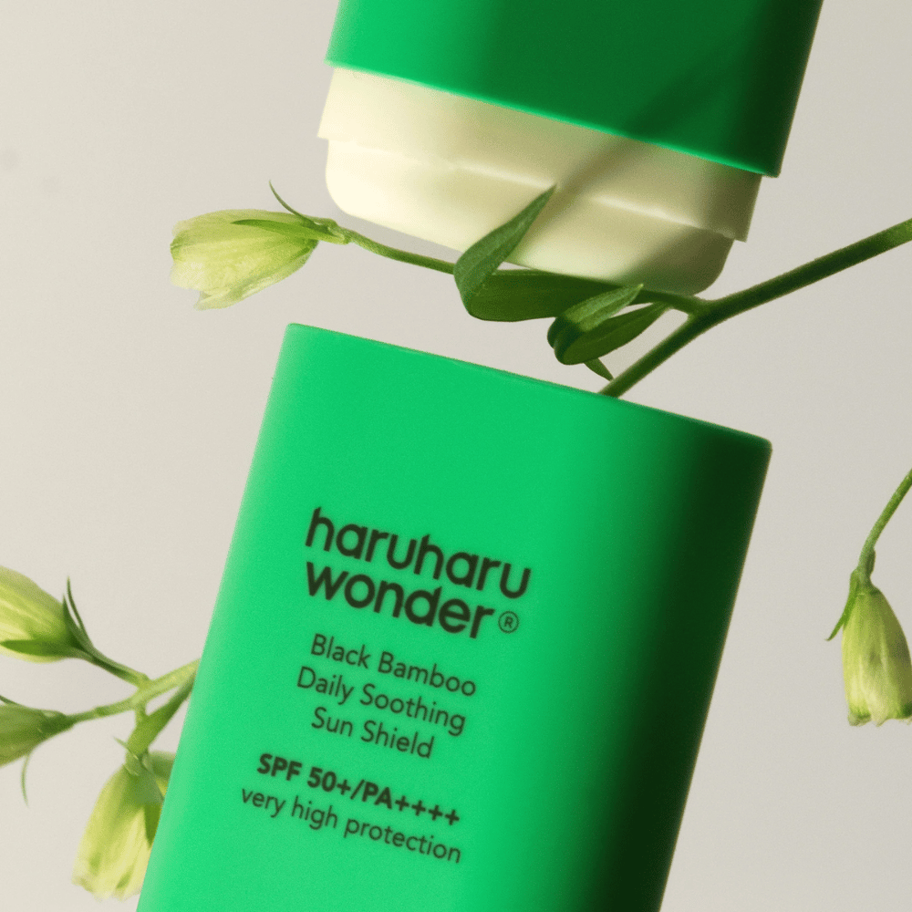 Primo piano di Haruharu Wonder Black Bamboo Daily Soothing Sun Shield – un solare verde in formato stick con SPF 50+ PA++++, circondato da dettagli di piante verdi.