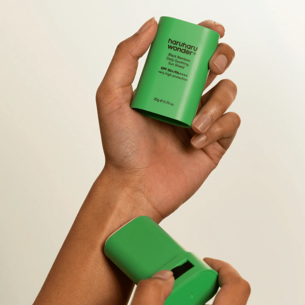Una persona applica Haruharu Wonder Black Bamboo Daily Soothing Sun Shield – un bastoncino solare verde con SPF 50+ PA++++ – sul polso.