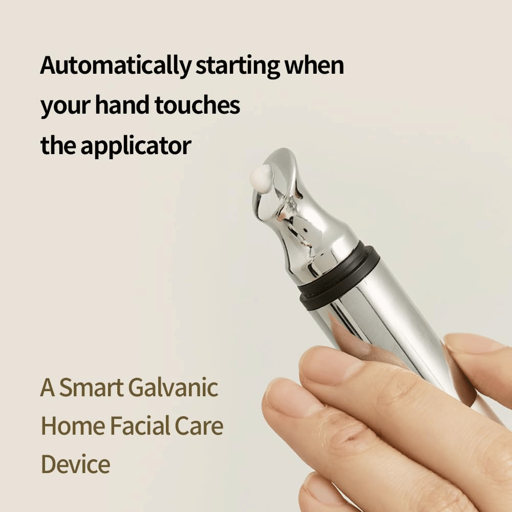 Primo piano di una mano che tiene un applicatore galvanico per crema contorno occhi con funzione di avvio automatico al tocco. Il testo sull'immagine descrive la funzione e il dispositivo come uno strumento intelligente per la cura del viso.