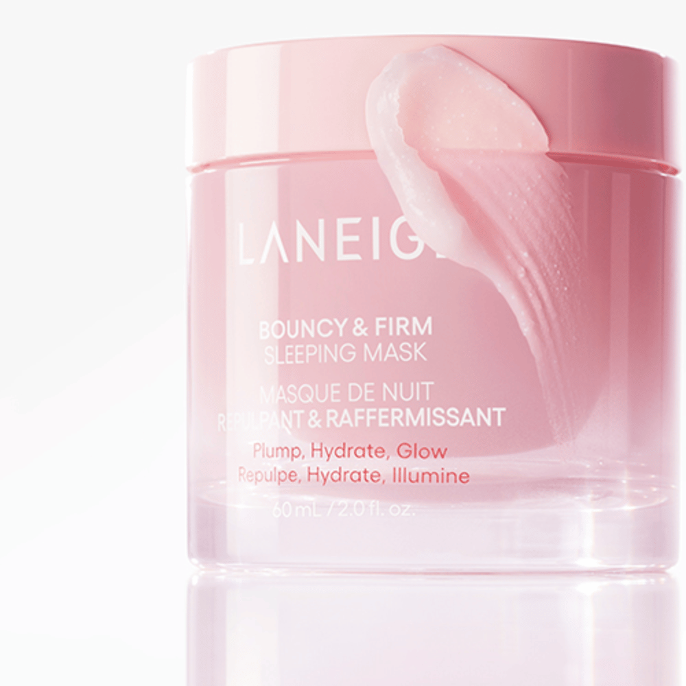 Primo piano di Laneige Bouncy & Firm Sleeping Mask in un barattolo rosa, con una parte della maschera applicata sul bordo del coperchio. Il prodotto è destinato a dare volume, idratazione e luminosità. Il barattolo contiene 60 ml e ha il testo "Plump, Hydrate, Glow."