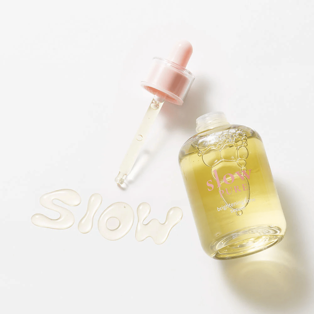 Slow Pure Brightening Tone Serum med öppen pipett, text skriven i serum på ytan: "Slow".