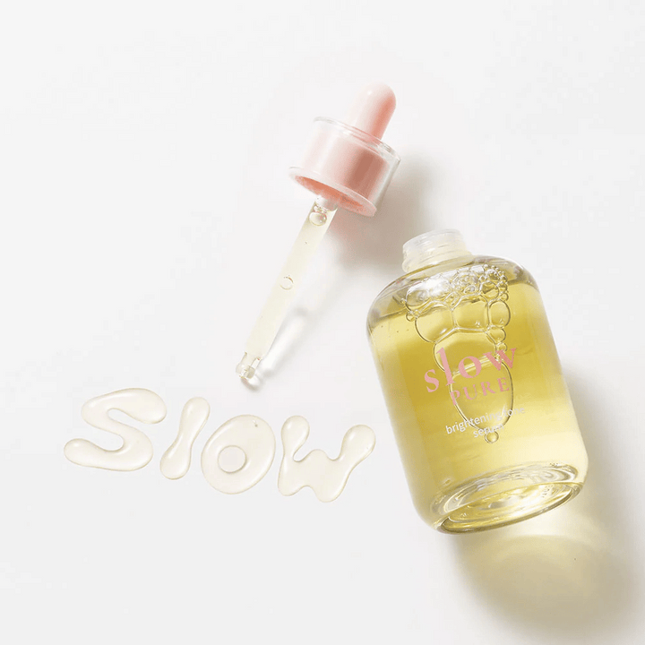 Slow Pure Brightening Tone Serum med öppen pipett, text skriven i serum på ytan: "Slow".