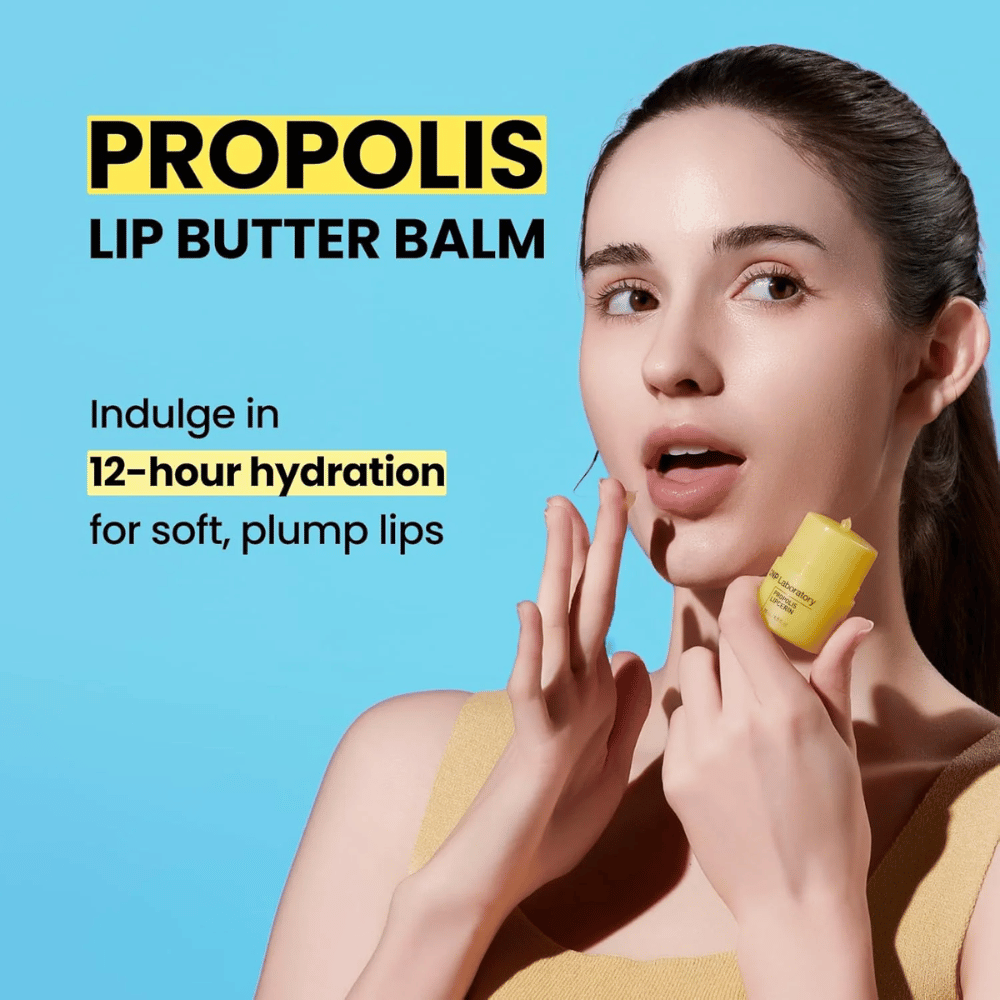 Una donna applica CNP Laboratory Propolis Lip Butter Balm, messa in risalto su uno sfondo blu. Il prodotto promette 12 ore di idratazione per labbra morbide e piene, mostrato con un tubo giallo che tiene in mano.