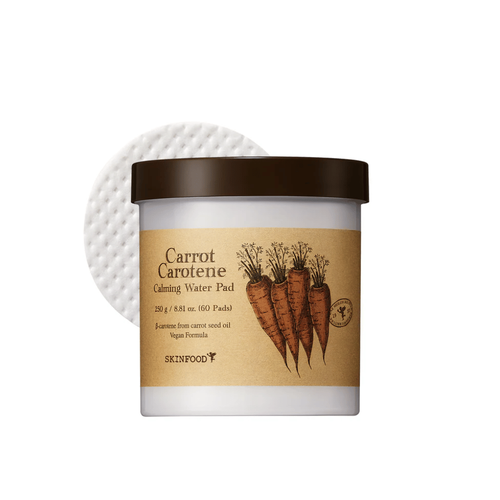 Un barattolo "Carrot Carotene Calming Water Pad" da SKINFOOD. Il barattolo contiene 60 tamponi ed è contrassegnato da un'immagine di carote. Il prodotto, a base di olio di semi di carota, è adatto ai vegani e progettato per lenire la pelle.