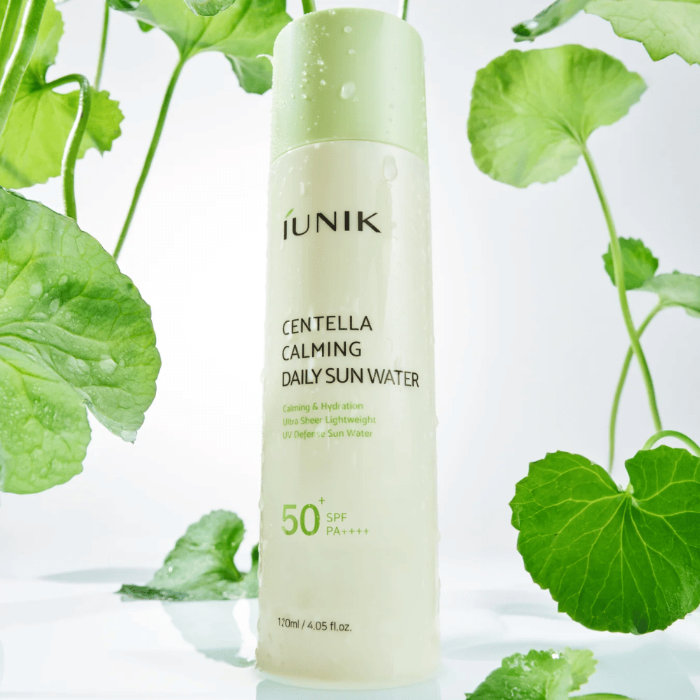 2. iUNIK Centella Calming Daily Sun Water SPF50+ PA++++ – protezione solare idratante con centella asiatica circondata da foglie verdi e gocce d'acqua