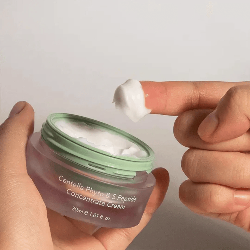 Mano che prende una dose di Centella Phyto & 5 Peptide Concentrate Cream da un barattolo.