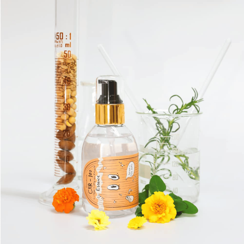 CER-100 Hair Essenza viso insieme a fiori e vetreria da laboratorio che mettono in risalto gli ingredienti e la cura dei capelli.