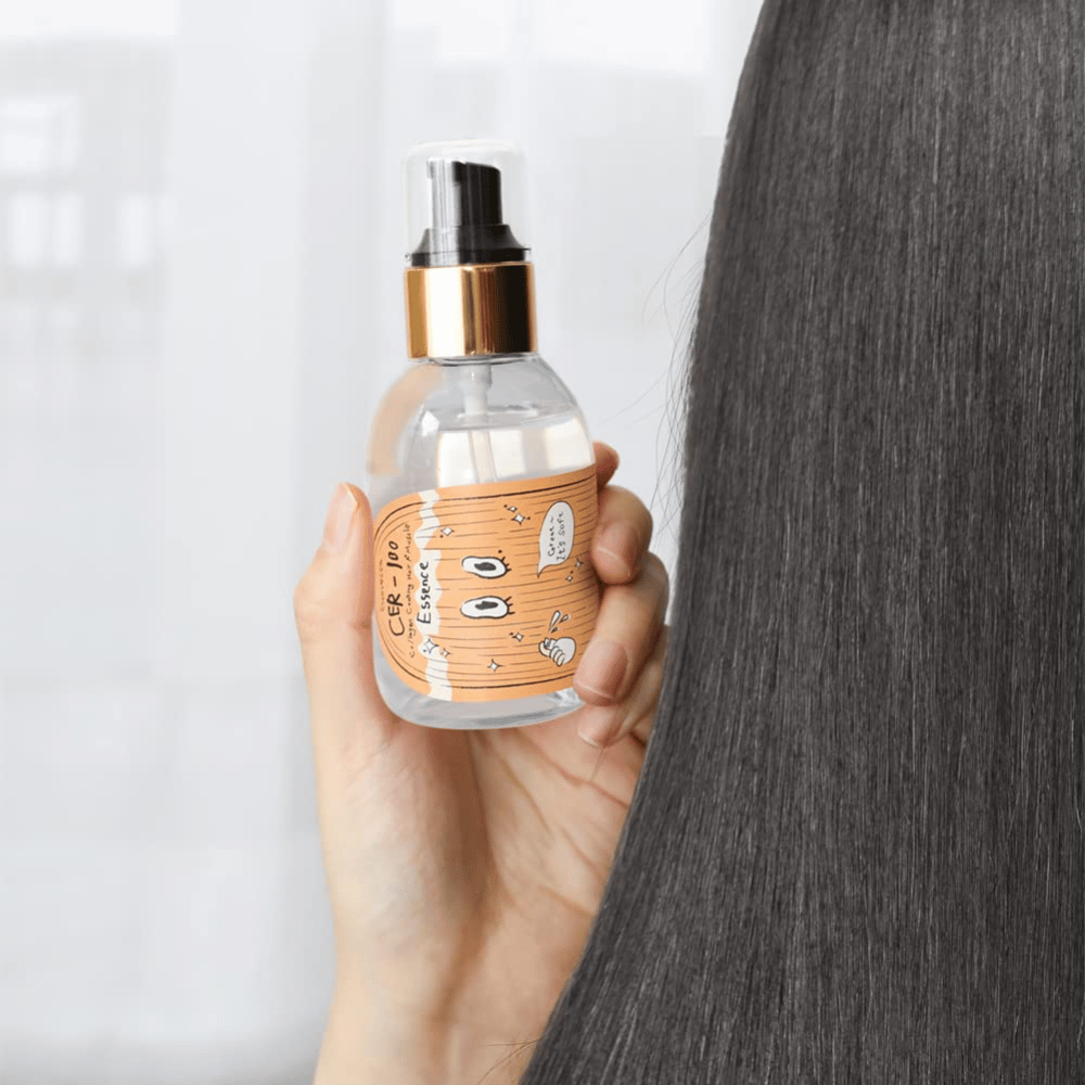 Una persona tiene CER-100 Hair Essenza viso accanto a capelli lunghi e lucenti per mostrare morbidezza e cura.