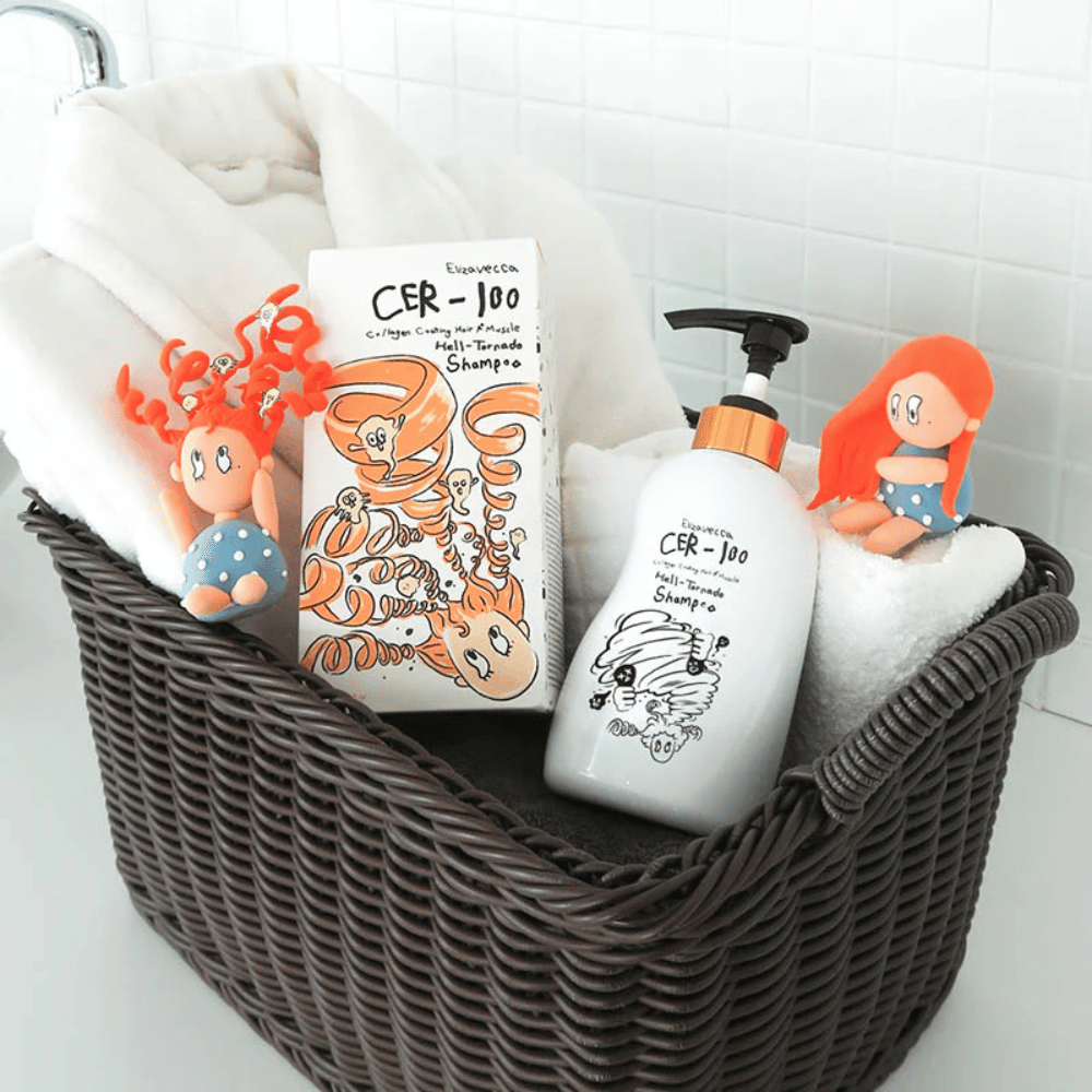 Immagine di presentazione con Elizavecca CER-100 Shampoo e la confezione del prodotto collocati in un cesto insieme ad asciugamani. Le figure giocose del design della confezione mettono in risalto lo stile unico e creativo del marchio.