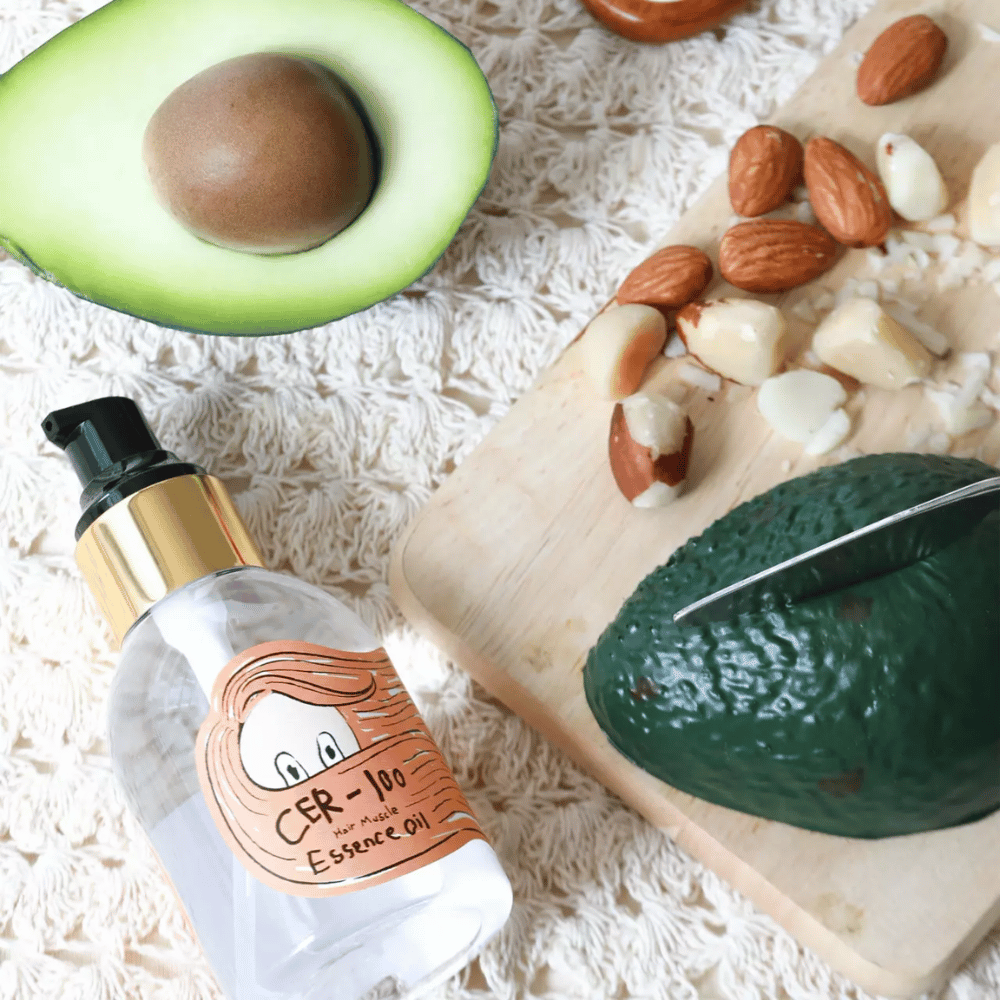 Elizavecca CER-100 Hair Muscle Essence Oil ingredienti – primo piano con avocado e oli vegetali che mostra un olio per capelli ricco di nutrienti che aiuta ad ammorbidire e nutrire i capelli.