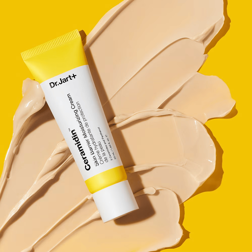 Tubo con Dr. Jart+ Ceramidin Skin Barrier Moisturizing Cream su uno sfondo giallo con crema sparsa.