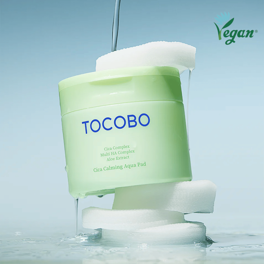 TOCOBO Cica Calming Aqua Pad posizionato tra toner pads con essenza viso che scorre. Il simbolo vegan sottolinea la formulazione vegana del prodotto e il suo profilo delicato sulla pelle.
