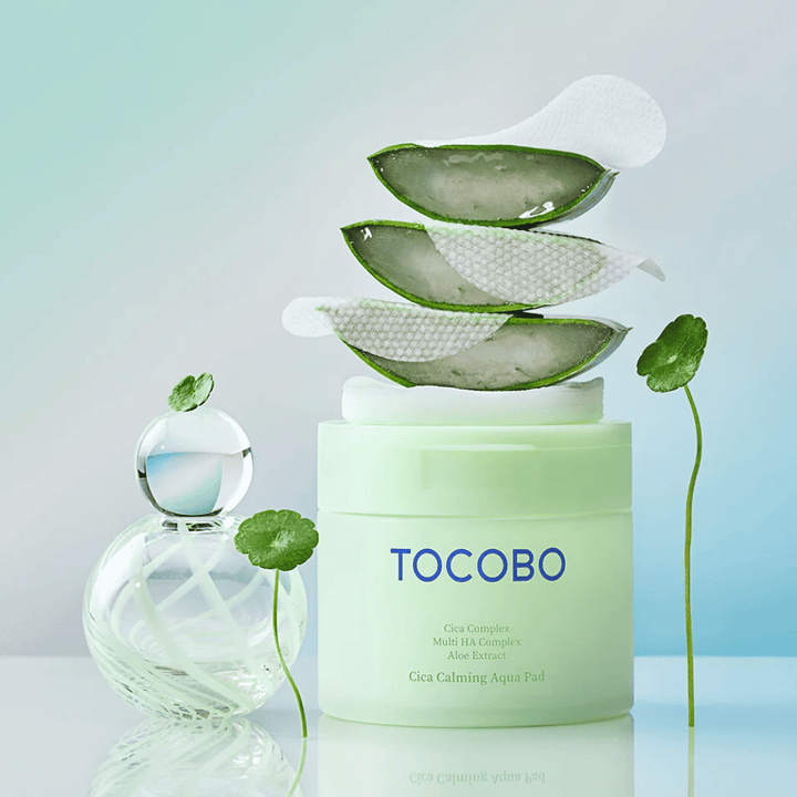 TOCOBO Cica Calming Aqua Pad è mostrato insieme a toner pads, aloe vera e centella asiatica. L’immagine mette in risalto gli ingredienti idratanti e lenitivi del prodotto.
