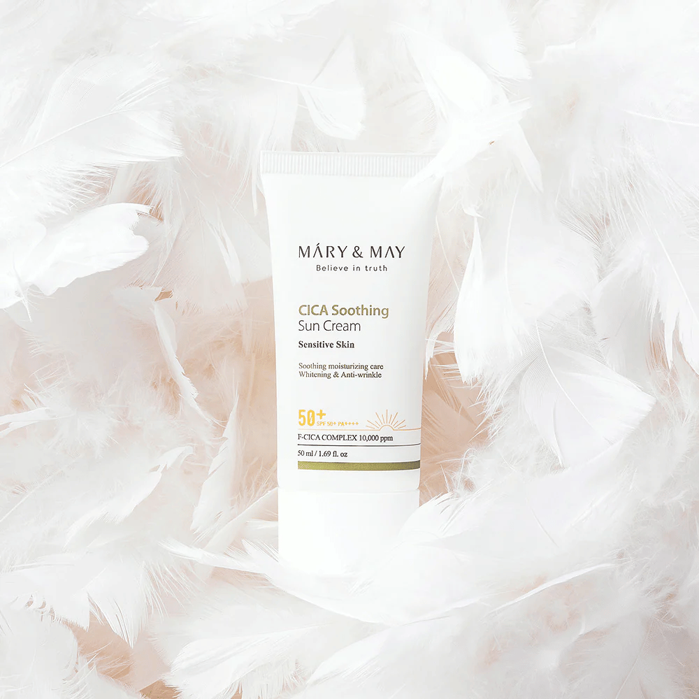 Mary&May CICA Soothing Sun Cream circondato da morbide piume bianche. L'immagine trasmette una sensazione di delicatezza, comfort e formula leggera adatta alla pelle sensibile.