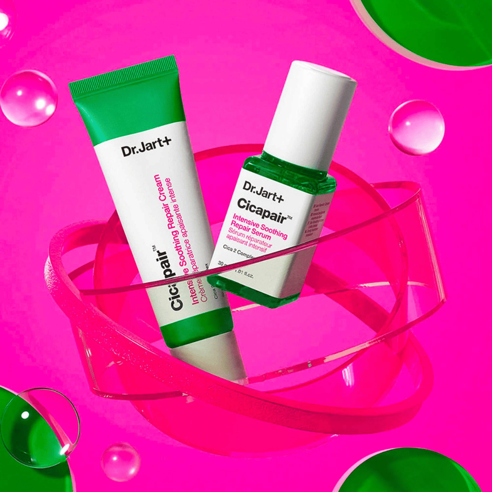 Dr.Jart+ Cicapair Intensive Soothing Repair Cream e Serum in confezioni verdi, posizionati su una base circolare rosa. I prodotti sono progettati per calmare e riparare la pelle irritata.