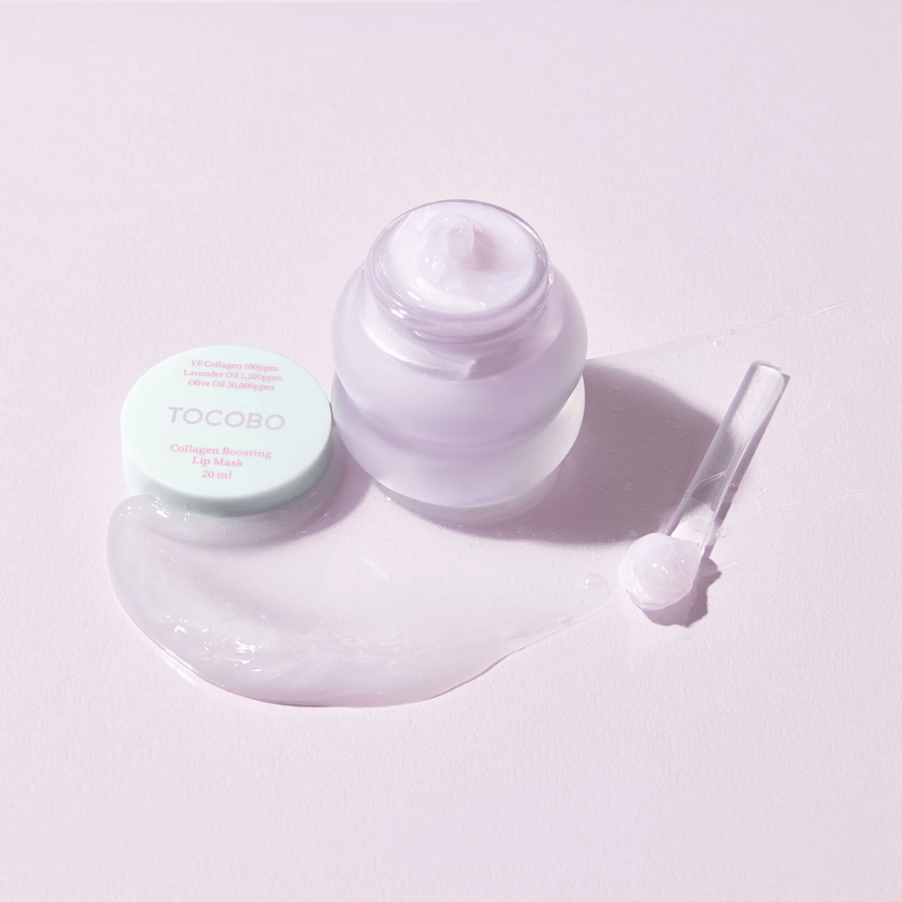 Barattolo aperto TOCOBO Collagen Boosting Lip Mask con spatola e crema viola sparsa su sfondo lilla chiaro.