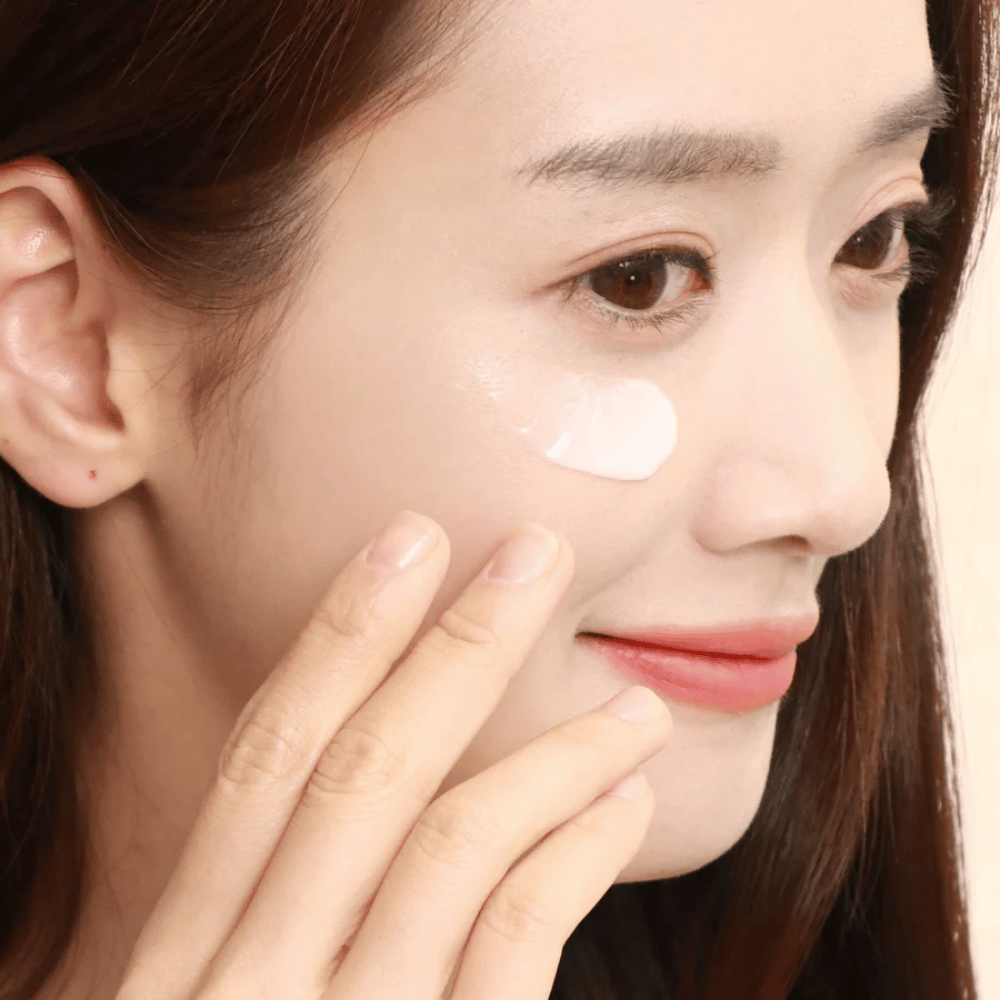 Donna applica crema contorno occhi sotto l'occhio con la punta delle dita – primo piano che mostra come il prodotto viene delicatamente massaggiato nella pelle per idratazione e cura.