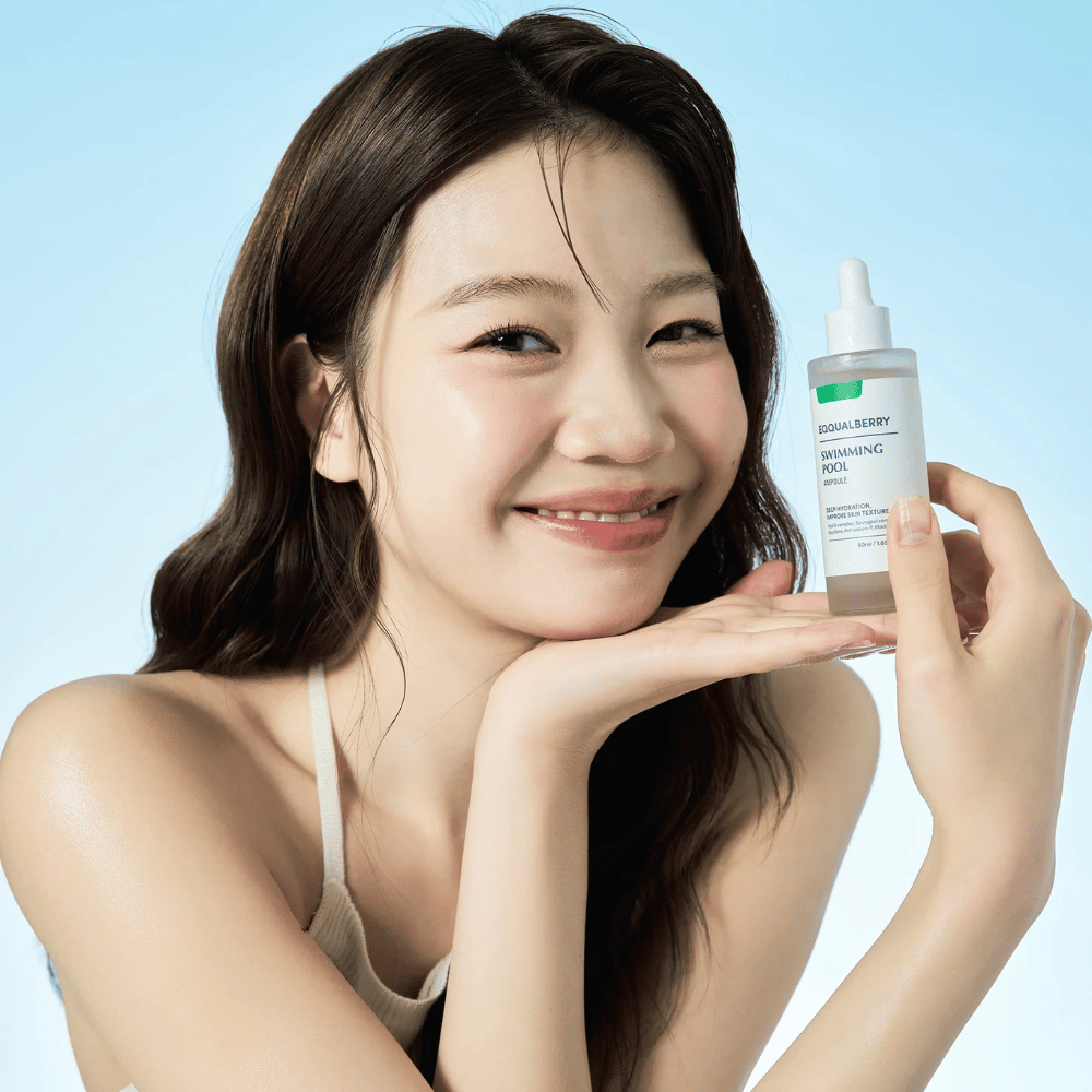 Donna sorridente che tiene in mano Eqqualberry Swimming Pool Ampoule, un prodotto idratante per la cura della pelle, con entrambe le mani su uno sfondo azzurro.