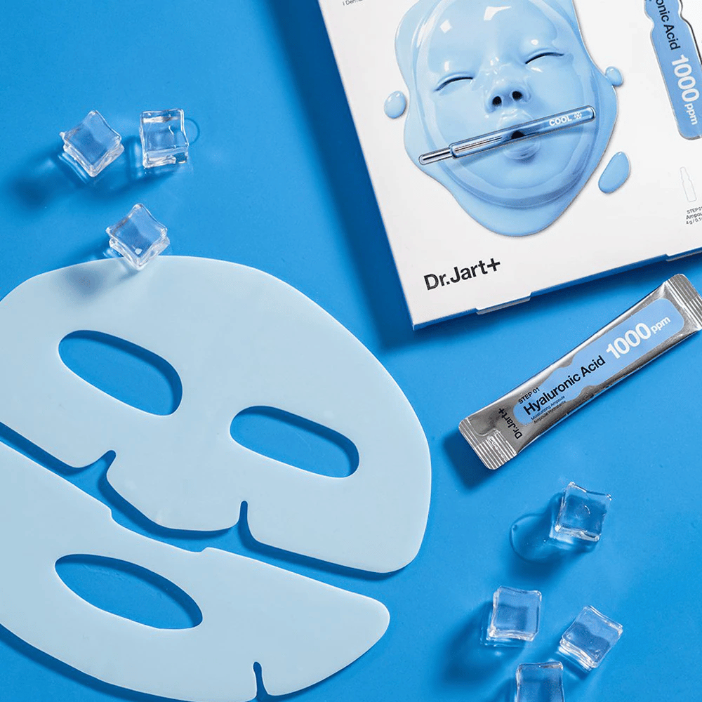 Dr.Jart+ Cryo Rubber Moisturizing Mask con maschera in gomma blu a due pezzi, cubetti di ghiaccio, fiala di acido ialuronico e confezione su sfondo blu.