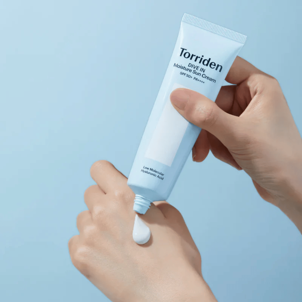 Torriden DIVE-IN Moisture Sun Cream SPF50+ PA++++ applicato sulla mano per mostrare la consistenza leggera e cremosa della crema solare idratante.