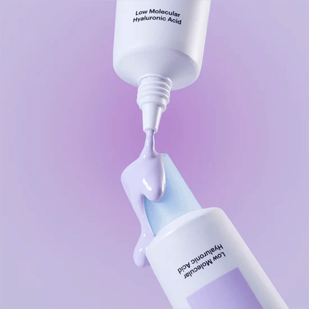 Primo piano di Torriden DIVE IN Tone Up Sun Cream Purple in cui la crema viola viene applicata dal tubetto per illustrare la consistenza del prodotto.