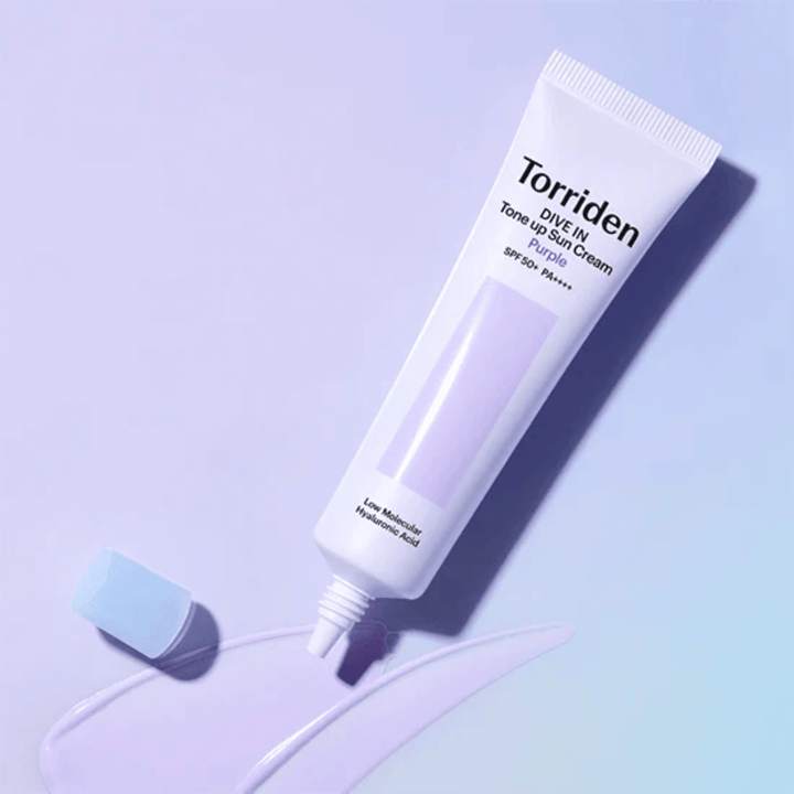 Tubetto aperto di Torriden DIVE IN Tone Up Sun Cream Purple con texture di crema solare tinta di viola che mostra la formula correttiva del colore del prodotto.