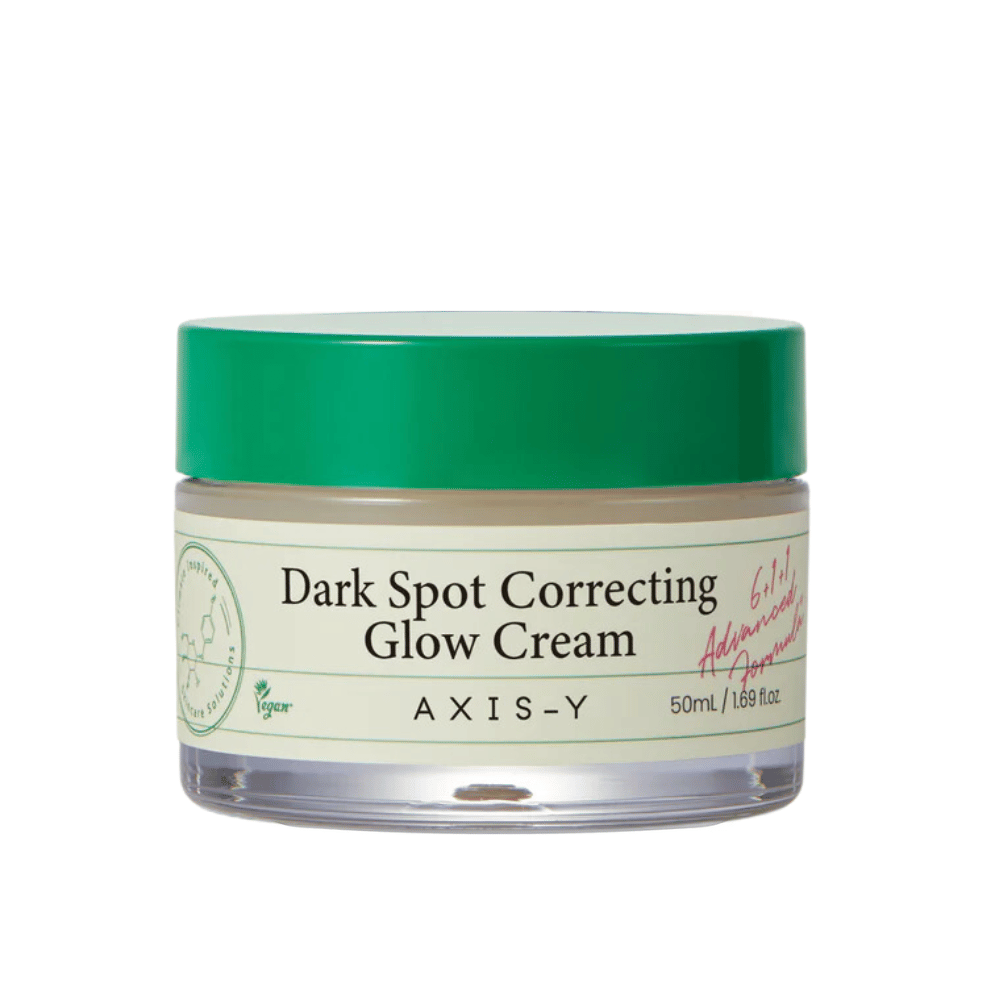 Un barattolo di "AXIS-Y Dark Spot Correcting Glow Cream". Questa crema è progettata per correggere le macchie scure e donare luminosità alla pelle. La confezione è elegante con una base trasparente e un coperchio verde accattivante.