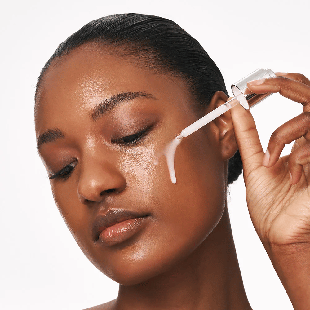 Una persona applica Deep Collagen Power Boosting Cream in Serum sulla guancia con una pipetta. Il siero rende la pelle più soda, idratata e luminosa.
