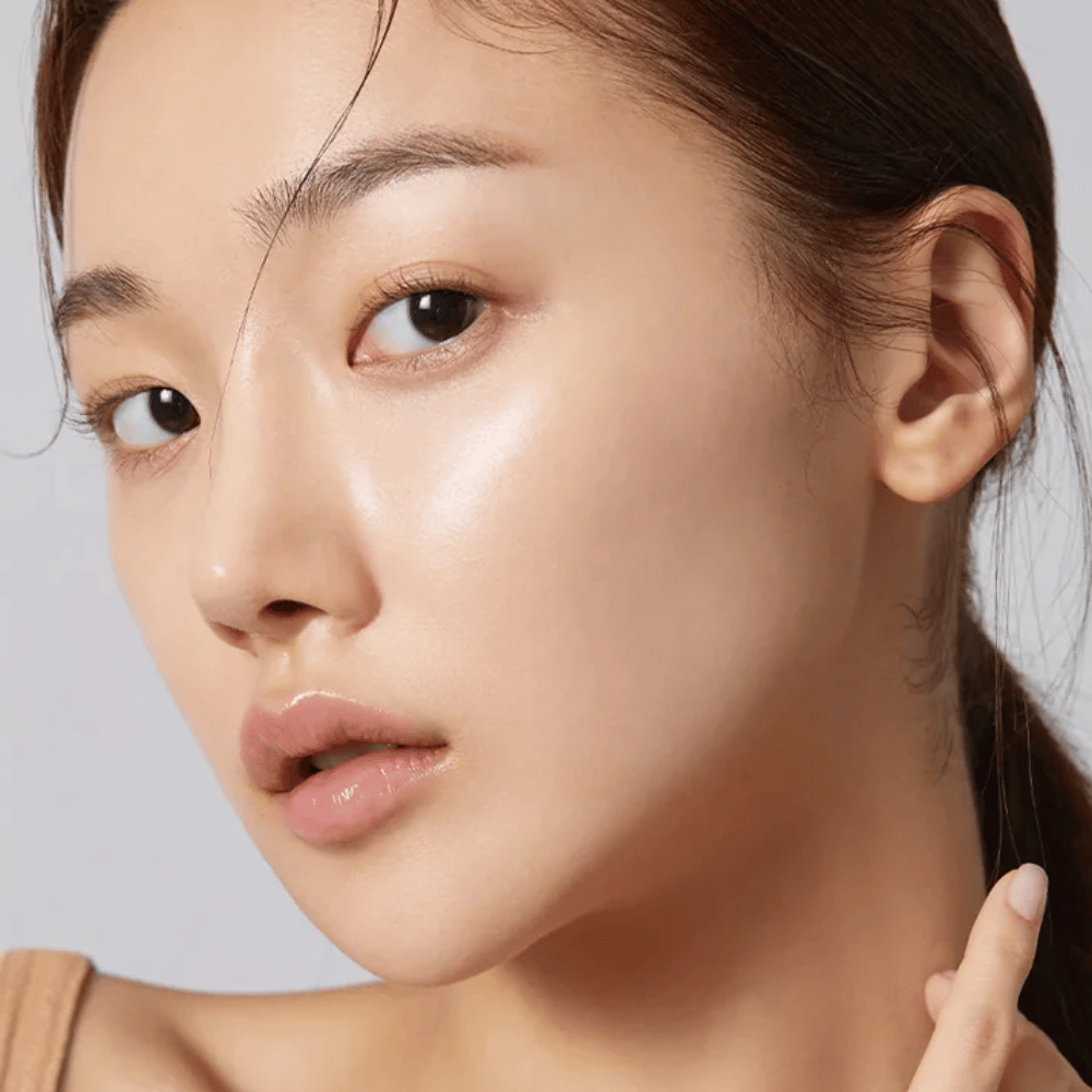 Primo piano di un modello con pelle chiara, idratata e luminosità naturale dopo l'uso di sheet mask coreana.