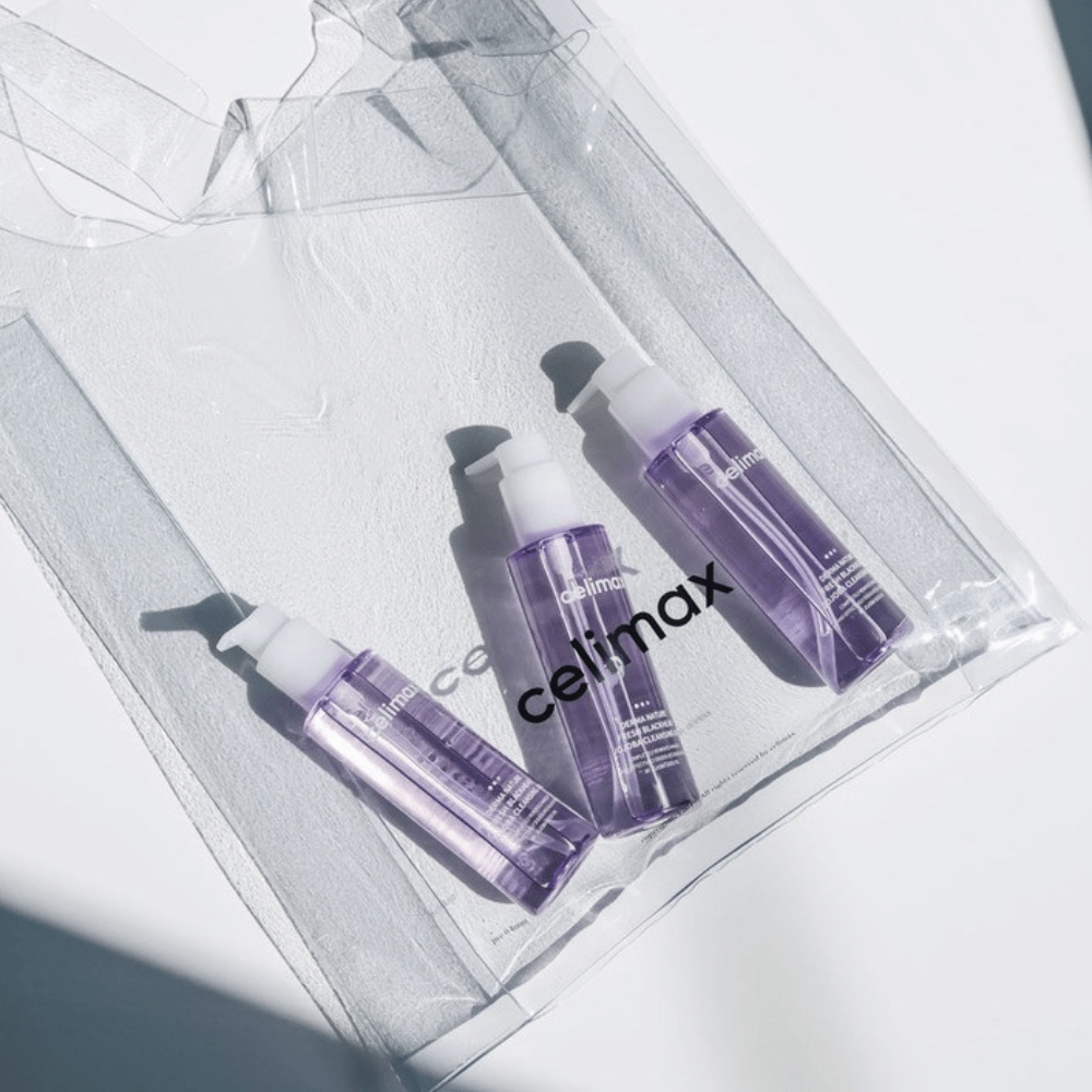 Tre bottiglie di Celimax Derma Nature Fresh Blackhead Jojoba Cleansing Oil in confezione viola, posizionate in una borsa trasparente con il logo 'celimax'.