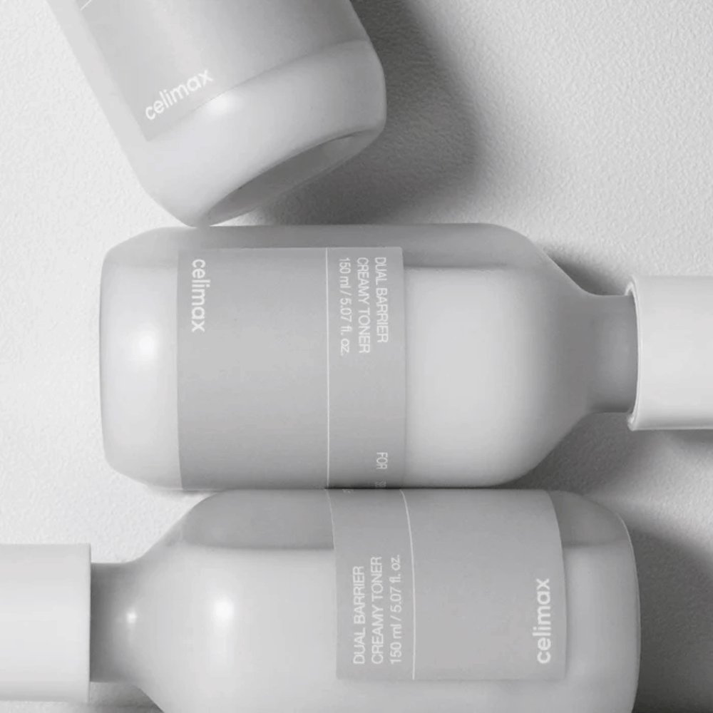 Tre bottiglie orizzontali di Celimax Dual Barrier Creamy Toner in un design minimalista con etichetta grigia e luce soffusa – perfetto per pelle sensibile e secca.